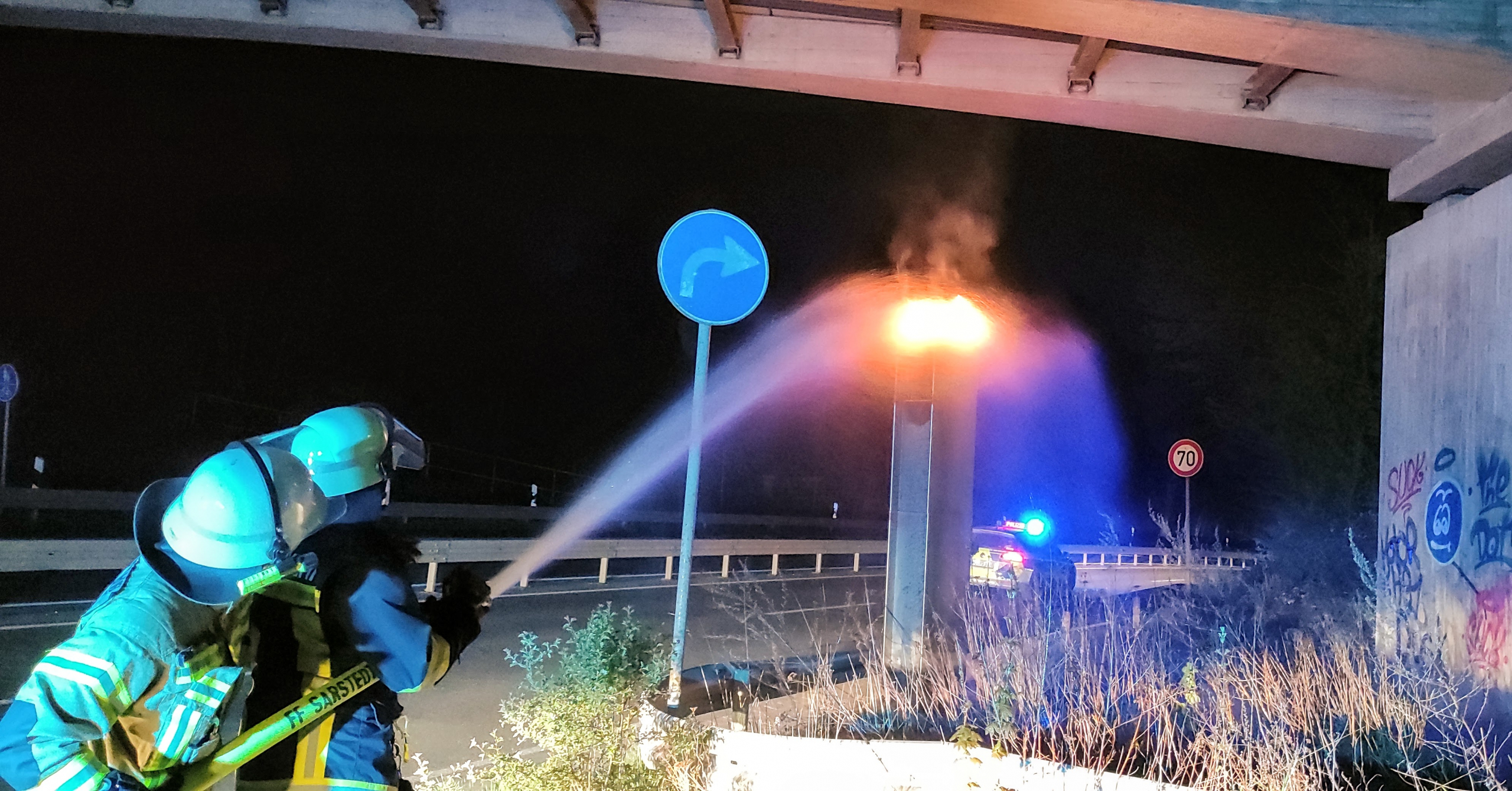 Feuerwehrleute löschen eine brennende Radarfalle